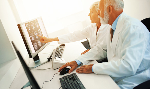 Two health professionals looking at a screen and discussing brain scans