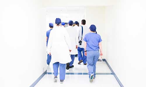 A group of doctors in scrubs walking along a corridor